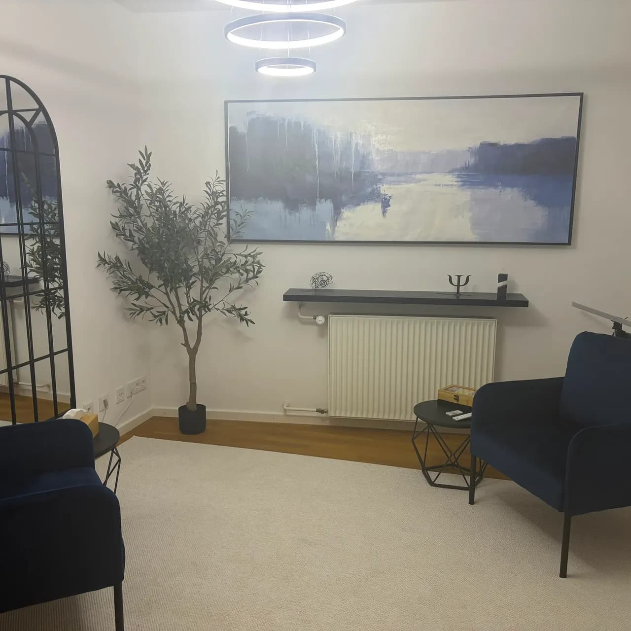 Therapieraum in Blau, mit zwei dunkelblauen Sesseln gegenüber unter einem großen abstrakten Gemälde