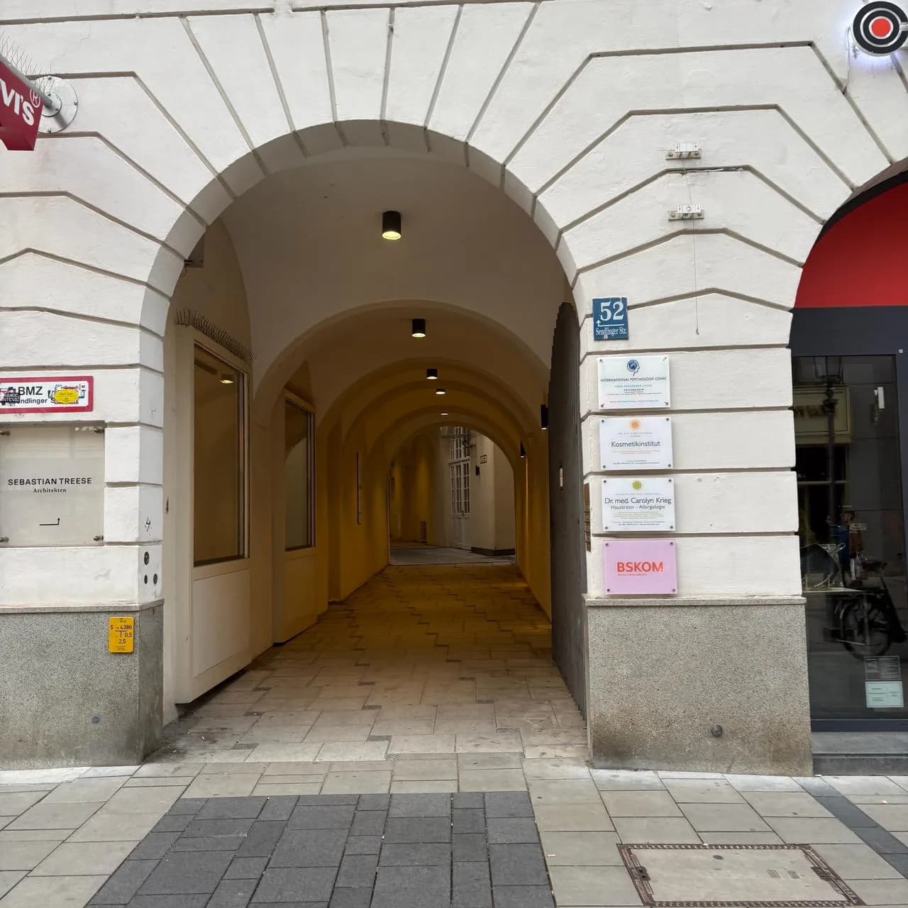 Torbogen-Eingang in der Sendlinger Straße 52, daneben das Namensschild der Praxis